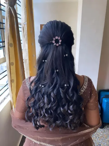 This half-updo features soft curls and is adorned with a sparkling circular accessory. It's a beautiful and elegant choice for a reception or engagement party.