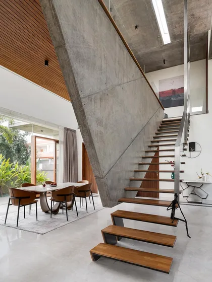 The interior is dominated by this sculptural, angular concrete wall that suspends a floating staircase. This element acts as a dynamic space divider between the dining area and the rest of the open-plan ground floor.