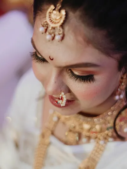 An artistic, high-angle shot focusing on the bride's beautiful eye makeup, bindi, and nath. These detailed portraits are perfect for capturing the artistry of the bridal look.