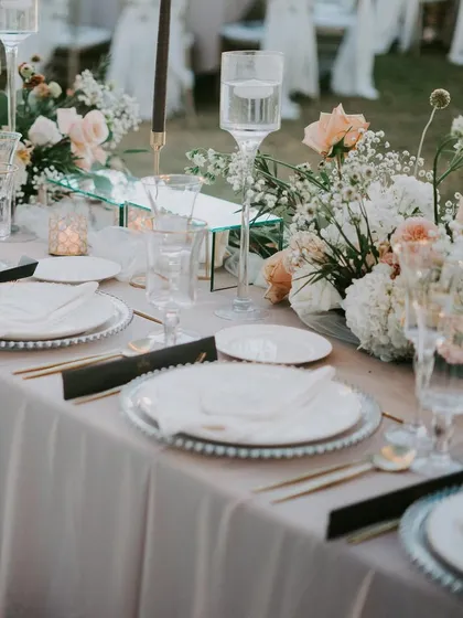 A beautifully arranged sit down dinner table with pastel florals and elegant silverware. We create sophisticated dining environments that allow the food and conversation to shine.