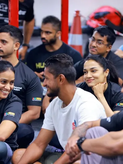 A moment of connection and camaraderie between athletes during a briefing. The support system is just as important as the workout itself.