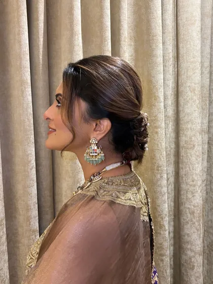 Another side view of the soft, textured updo. This angle highlights the gentle sweep of the hair and the careful placement of the pearl accessories.
