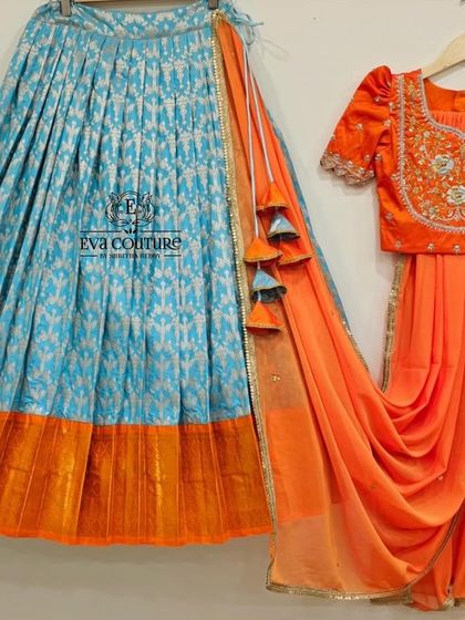 A vibrant half-saree set with a blue Ikat-style lehenga and a contrasting orange blouse and dupatta.