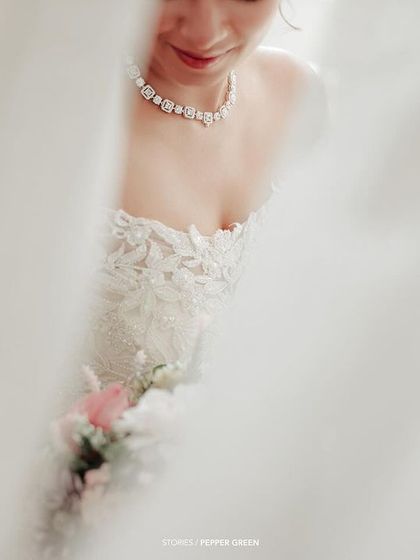 An artistic, soft-focus shot of the bride through a curtain, creating a mysterious and romantic bridal portrait.