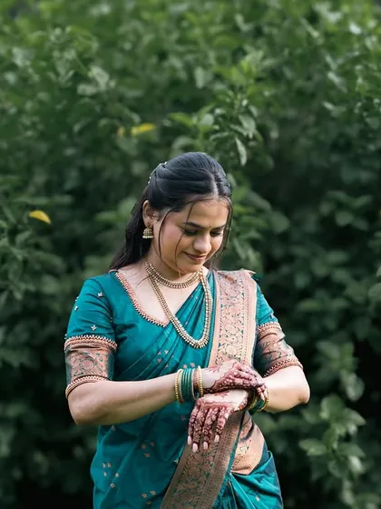 A bride in a gorgeous teal saree, captured in a natural, outdoor setting.