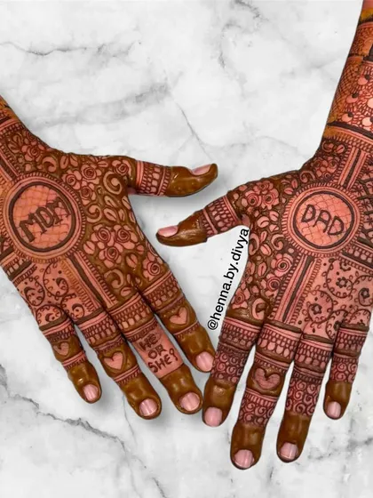 This baby shower design includes a 'He or She' element on the fingers, with 'Mom' and 'Dad' as the central focus on the palms, surrounded by dense, traditional floral work.