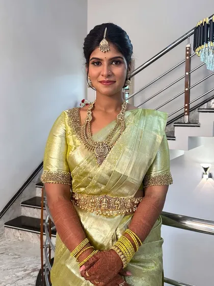 A simple and elegant engagement look. The makeup is soft and dewy, with a focus on flawless skin to complement her beautiful lime-green silk saree and traditional jewelry.
