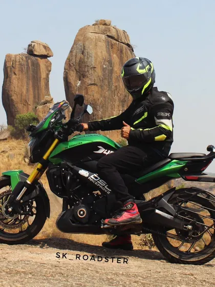 A full side view of the rider and his green Dominar, giving a thumbs-up to the camera.