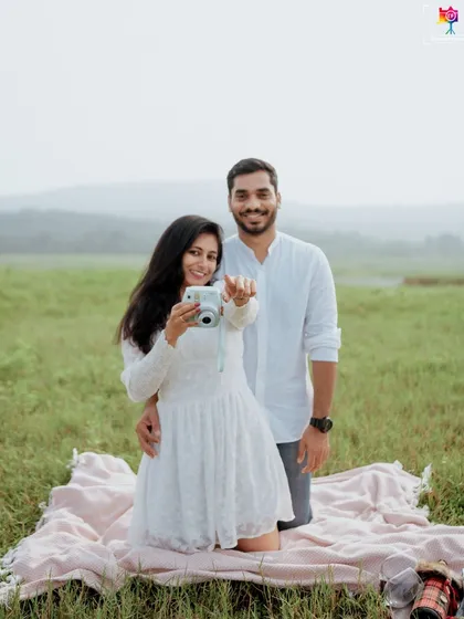 A fun and interactive shot from a picnic-themed session, where the bride-to-be playfully points her instant camera, capturing a memory within a memory.