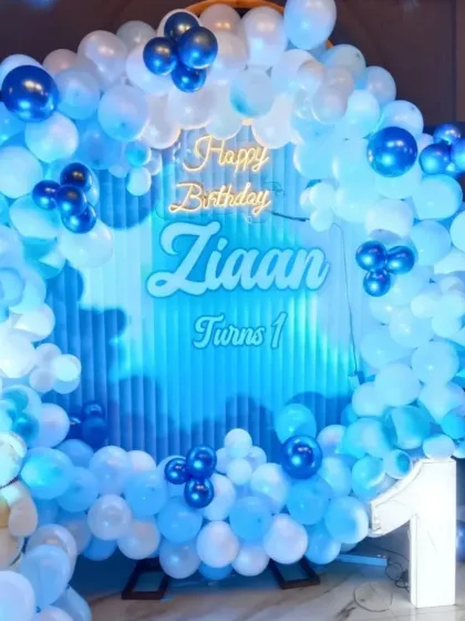 Celebrating Ziaan's first birthday with this cool blue and white theme. The setup includes a personalized neon sign, a big light-up number '1', and a cute teddy bear, making it a perfect backdrop for cake cutting.