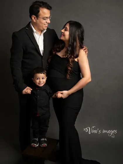From three to four. This classic family maternity portrait in the studio captures the excitement of a growing family, with their young son standing proudly between his parents.