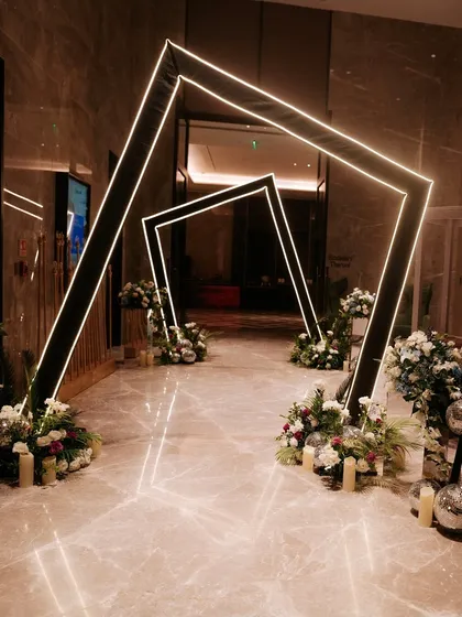 A view of the modern LED light tunnel at night. The geometric frames are illuminated, creating a futuristic and high-impact walkway for guests entering the event.
