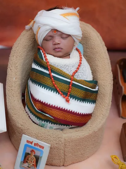 Sleeping peacefully, our little Vitthal is surrounded by symbols of devotion, including a miniature 'Haripath' book. Every prop is chosen to add meaning to the photograph.