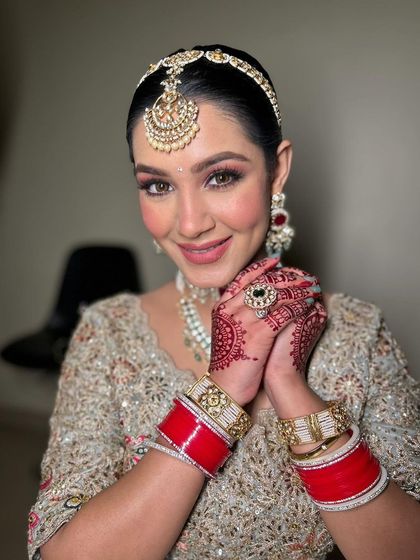 A happy bride with her hands clasped. The focus is on her radiant smile and the beautiful, clean makeup that enhances her natural features.