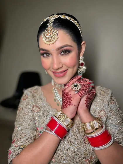 The joy of a bride, complete with her chooda (bridal bangles). The makeup is designed to last through all the ceremonies and celebrations, keeping her looking fresh and beautiful.