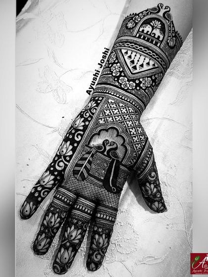 An intricate Indian designer mehendi for a bridesmaid. This style combines traditional elements like peacocks and lotuses with modern layout and flow, covering the hand in a stylish way.