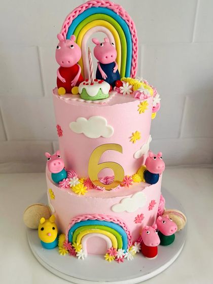 A grand two-tier Peppa Pig cake with the whole family, rainbows, and lots of fun details.