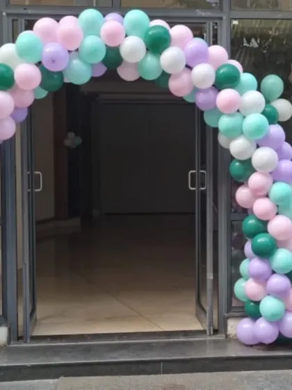 A mermaid-themed balloon arch in pastel shades of green, purple, and mint.