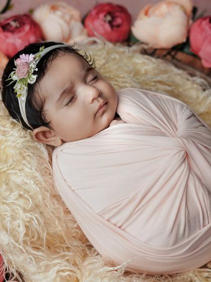 A perfect little blossom. This swaddled baby, surrounded by a wreath of flowers, is a beautiful and artistic way to capture your newborn.