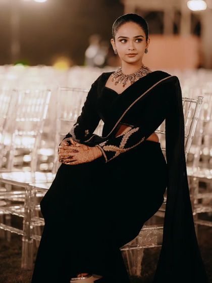 A client looking chic and elegant in a custom all-black velvet lehenga saree. The full-sleeve blouse features subtle embroidery on the arms.