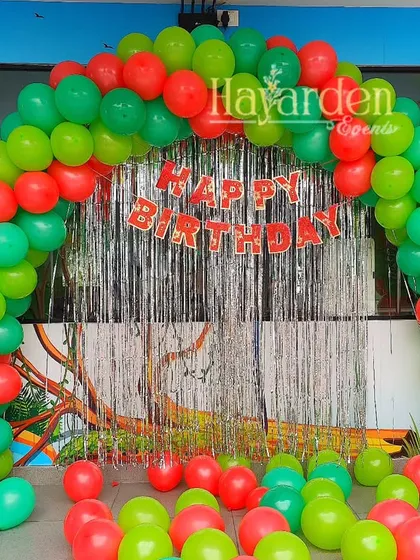 A classic balloon arch in red and green with a fringe backdrop. This is a simple, festive, and budget-friendly option for any celebration.