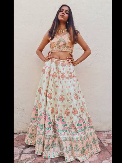 A strong and stylish pose that showcases the full A-line silhouette of the pastel green lehenga.