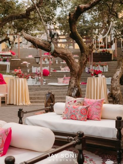 This lounge area for a Mehfil-e-Mehendi features traditional Indian daybeds with plush white cushions and vibrant pink pillows. The setting is both regal and relaxed, perfect for an evening of music and celebration.