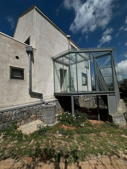 A close-up of the glass-enclosed bridge connecting two parts of the 'Wildgrass' home. This transparent link allows for movement through the house without losing the sense of being in the landscape.