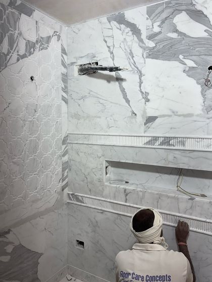A craftsman meticulously installs marble tiles and decorative trim in a future washroom. The attention to detail at this stage is what ensures a flawless and luxurious final result.
