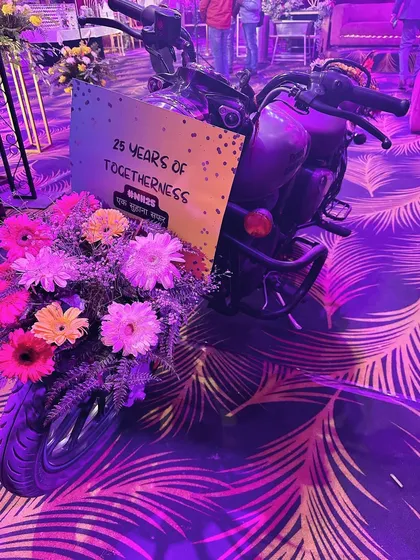 A fun and unique photo-op for an anniversary party, featuring a vintage motorcycle decorated with flowers and a sign celebrating "25 years of togetherness".