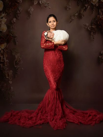 A stunning solo portrait of a mother in a red lace gown holding her newborn. This shot celebrates the mother and her special connection with her baby.
