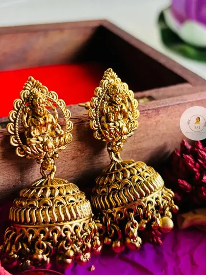 A pair of exquisite temple jhumkas with a Goddess Lakshmi motif at the stud. These earrings are a statement piece on their own or as part of a full set.