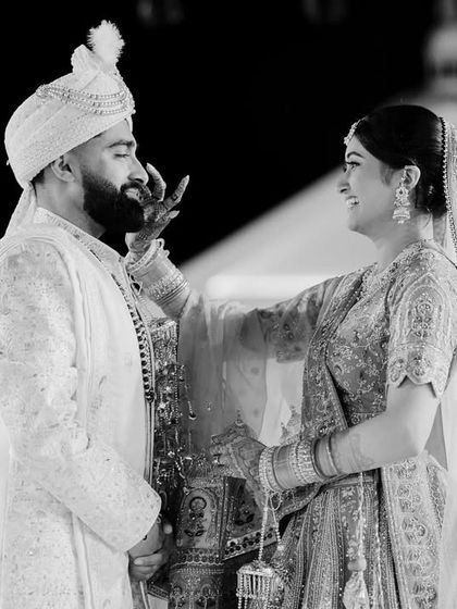 A sweet, candid moment during the Varmala ceremony. The bride's gentle touch and the groom's smile tell a story of love and partnership.