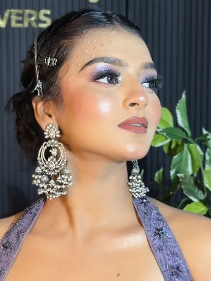 A close-up of the purple glitter eye makeup, showing the delicate placement of crystals on the temple for an ethereal touch.