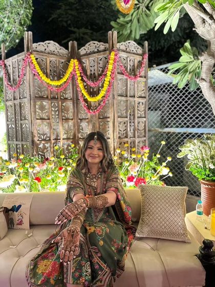 A beautiful bride posing with her intricate mehandi. The colorful background and her elegant attire make for a perfect picture.