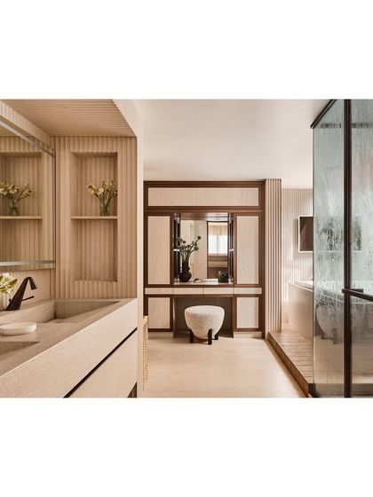 A view into the expansive master bathroom, showing the seamless transition from the vanity area to the wet zone. We used fluted wall panels and a consistent light wood finish to create a cohesive, spa-like environment.