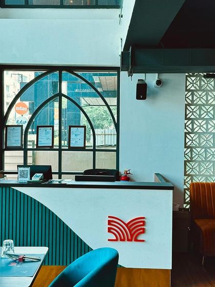 Our reception desk, featuring modern design with teal and white curves and our signature logo. This is where we welcome you to your fine dining experience.