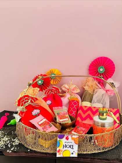 This large gold wire basket is perfect for a family-sized Holi hamper. It's packed with colorful potlis, a pichkari, thandai, and other treats for everyone to enjoy.