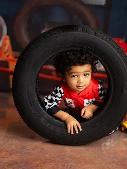 A little racer peeking through a tire. This car racing theme is perfect for a high energy toddler's birthday shoot.