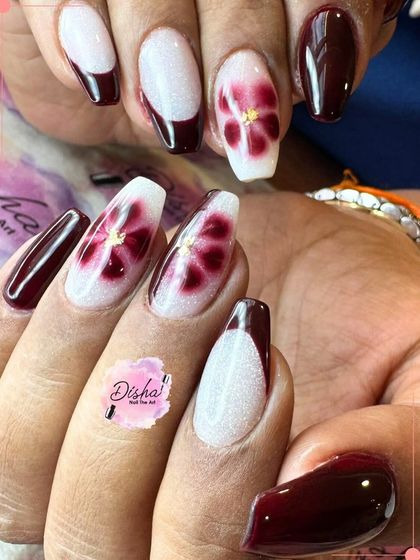 Bold and beautiful. This design combines deep maroon polish with intricate floral art on a shimmery white base, creating a stunning contrast.