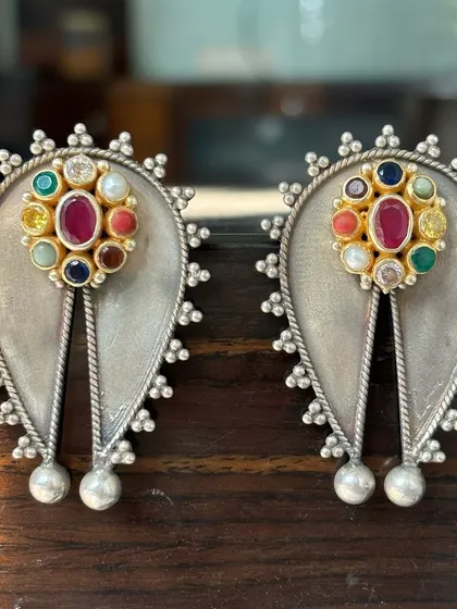 A top-notch example of my fusion earring design. These feature a matte silver base with a nine-stone 'Navratna' style arrangement in a gold-plated setting, combining traditional concepts with modern aesthetics.