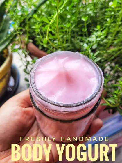 Holding a jar of my freshly made Cherry Blossom Body Yogurt. It has a lovely pink hue and a smooth texture that your skin will love.