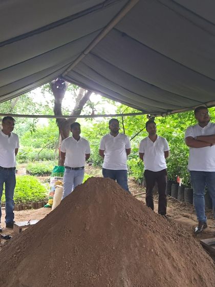 The team from Valvoline Cummins stands by a large pile of soil mix at our Aranya nursery, ready to prepare bags for new saplings.