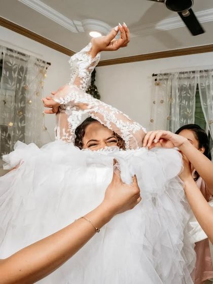 A playful and chaotic moment as the bridesmaids help the bride into her voluminous wedding dress. It's these fun, real moments that make the day.