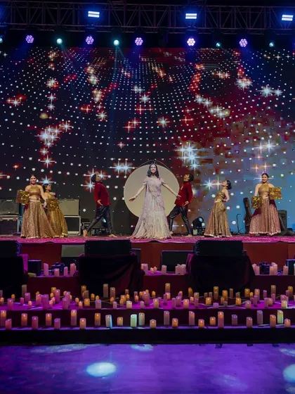 A wide shot of a performance during the 'Chandni Ratein' sangeet. The entire stage, from the candle-lined floor to the starry LED background, was designed to immerse everyone in the magical, moonlit theme.