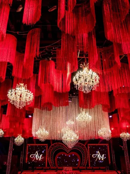 A grand view of the entire hall, capturing the scale of the ceiling installation, the numerous chandeliers, and the heart-shaped stage in the distance.