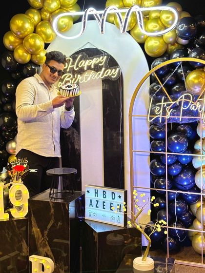 Celebrating the big 1-9. This young man poses with his cake in front of a stylish black, white, and gold decor theme, complete with neon signs. Our setups are perfect for creating those cool, Instagram-worthy birthday shots.