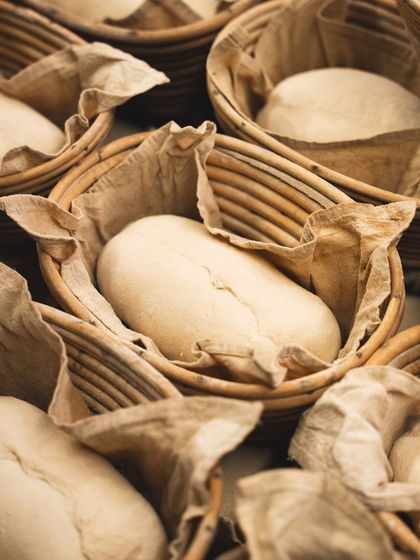 Sourdough loaves resting in banneton baskets. This proofing method helps the bread hold its shape and develops the classic sourdough flavor profile.