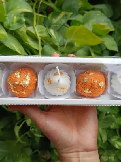 A hand-held view of the laddoo and modak gift set, showing the convenient and attractive packaging.