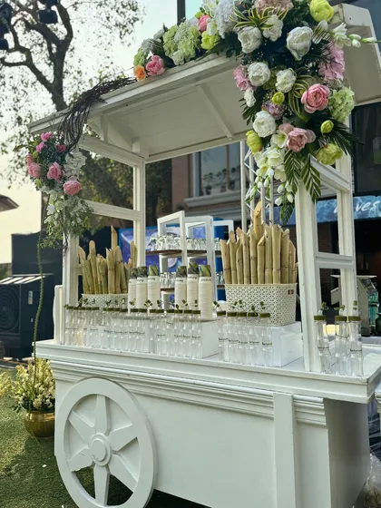 A refreshing sugarcane juice station set up on an elegant white cart. Decorated with floral arrangements, it provides a delightful and visually appealing welcome for guests.